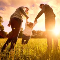 Mother and father who debated egg donation vs adoption holding child's hand in a sunny field | RSC SF Bay Area