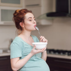 Pregnant woman following a healthy pregnancy diet savors what she is eating from a bowl | RSC of the SF Bay Area